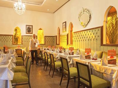 Elegant dining room with green chairs and decorative walls in a hotel.