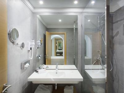 Modern bathroom with sink, large mirror, and shower area in a hotel room.