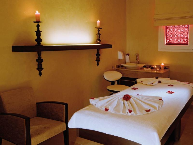 A relaxing massage room with a massage table, candles, and a comfortable chair.