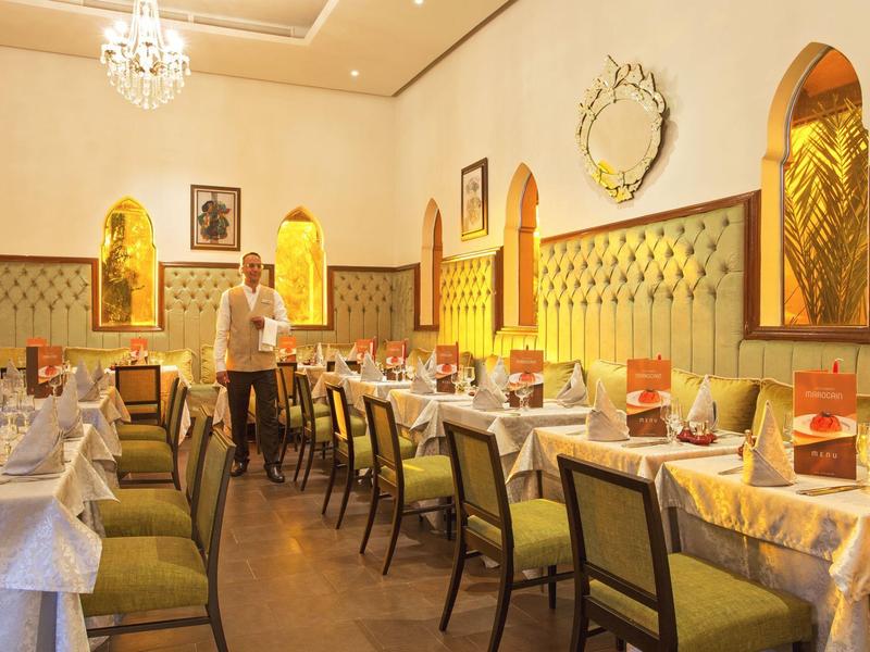 Elegant dining room with green chairs and decorative walls in a hotel.