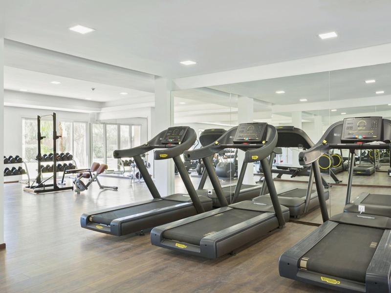 Bright gym with treadmills and weights along the wall.