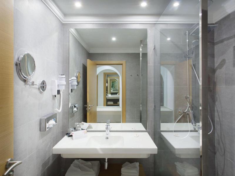 Modern bathroom with sink, large mirror, and shower area in a hotel room.