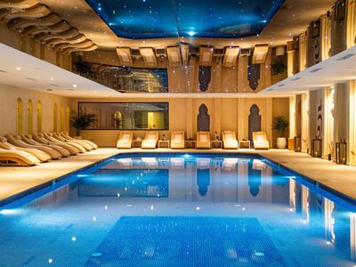 Piscine intérieure moderne avec éclairage bleu et chaises longues confortables dans un hôtel.
