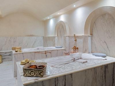 Salle de spa luxueuse en marbre avec baignoire, îlot en marbre et éclairage chaud.
