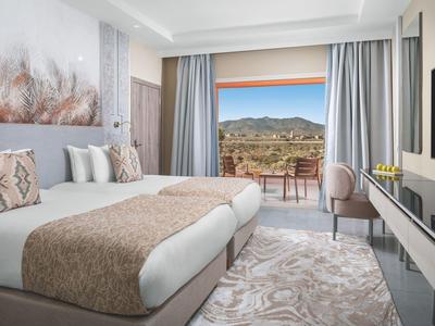 Chambre d'hôtel moderne avec vue sur la montagne et balcon avec chaises.