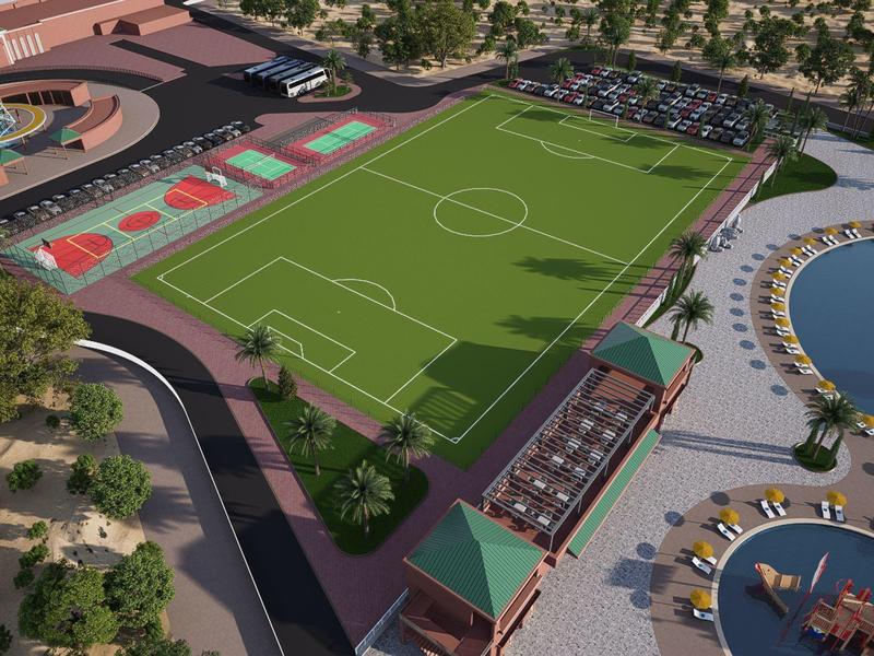 Grande campo da calcio accanto a campi da tennis e area piscina in resort vacanze.