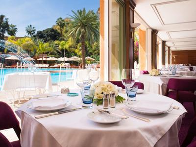 Eleganter Tisch mit weißer Tischdecke und Blick auf den Poolbereich eines Hotels.