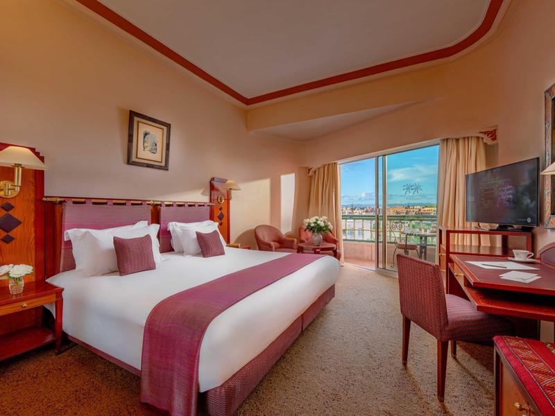 Przytulny pokój hotelowy z dużym łóżkiem, biurkiem i balkonem z widokiem