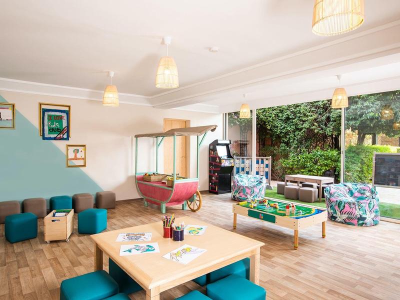 Salon moderne avec poufs et grande fenêtre donnant sur une terrasse verte à l'hôtel