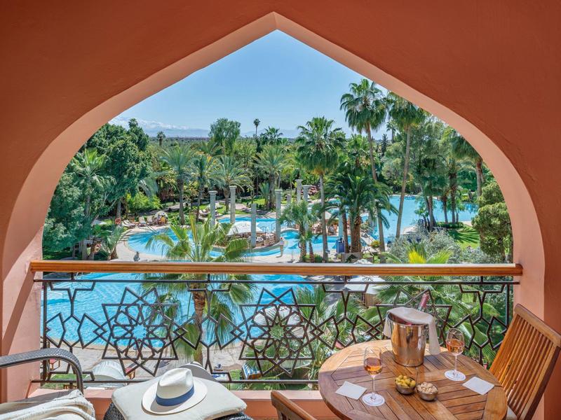 Balcon avec vue sur la piscine et les palmiers dans une station balnéaire tropicale.