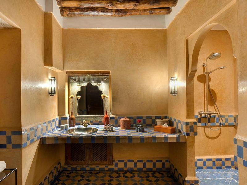 Warm traditional bathroom interior with illuminated mirror and decorative tiled floor.