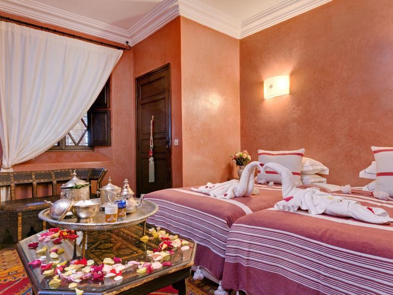 Cozy room with two beds, decorated with towels and rose petals.