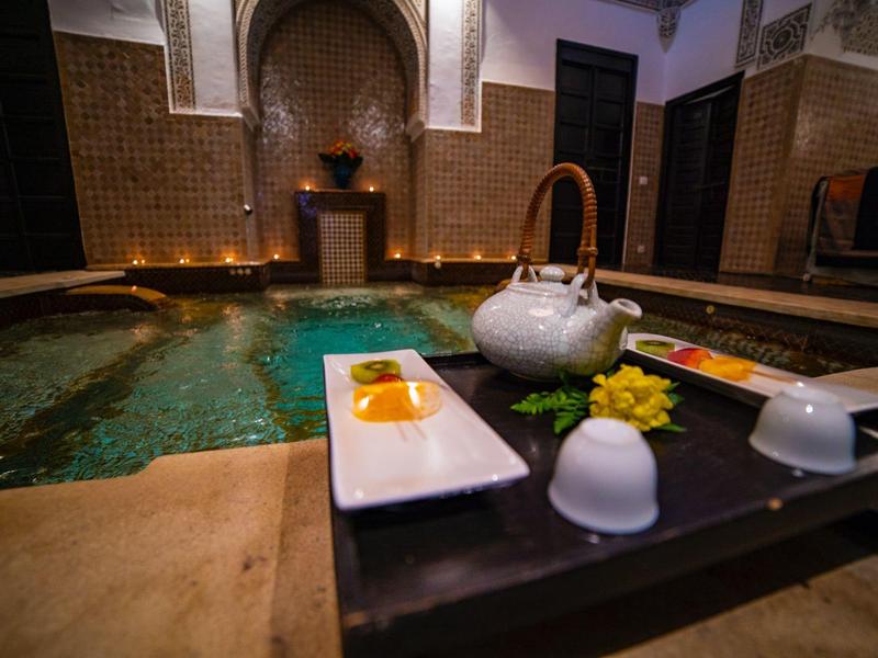 Traditional hammam with flowing water and candles in a Moroccan interior.