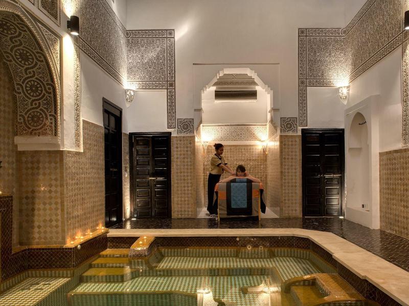 Interior of a traditional hammam with mosaic pool and tranquil ambiance.