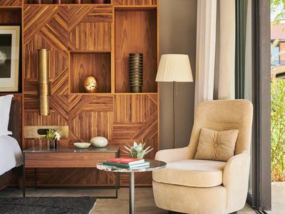 Modern hotel room with wooden panels, comfy armchairs, and natural light.