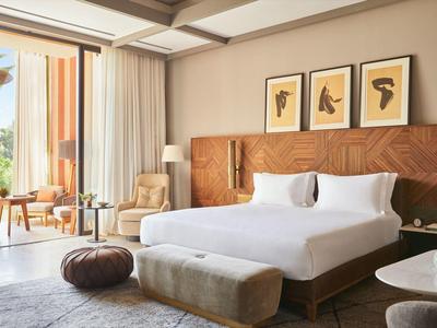 Modern hotel room with large bed, wall art, and balcony seating area.