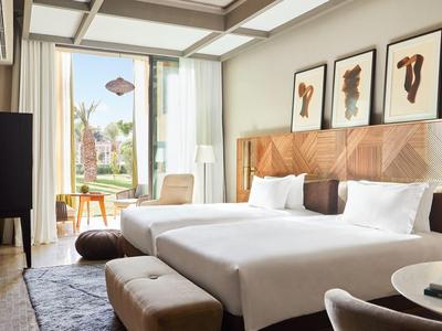 Bright hotel room with double bed, wood accents, and large window overlooking a terrace.