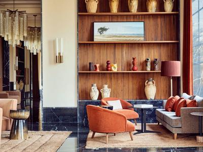 Eleganter Hotel-Lounge-Bereich mit modernen Sesseln, dekorativen Vasen und einem großen Fenster.