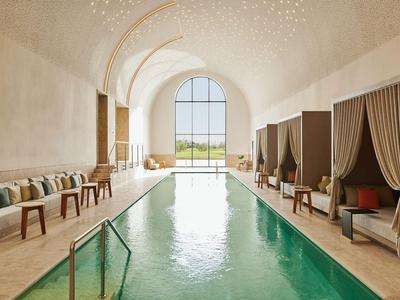 Innenpool mit elegantem Bogenfenster, bequemen Sitzbereichen und gedämpftem Licht.