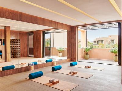 Heller Yoga-Raum mit Matten, Rollen und großen Fenstern, die auf eine Terrasse blicken.