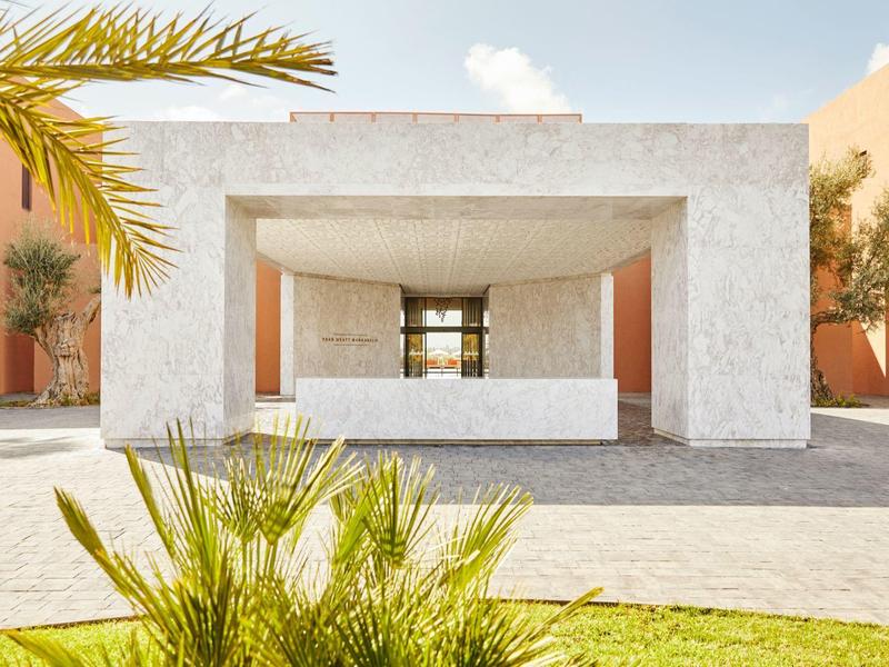 Modern building entrance with white stone frame and landscaped outdoor area in daylight
