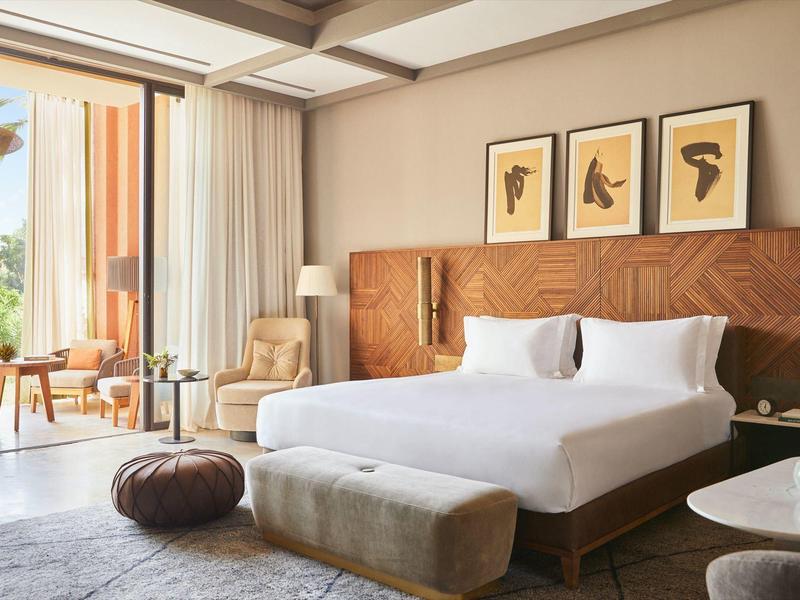 Modern hotel room with large bed, wall art, and balcony seating area.