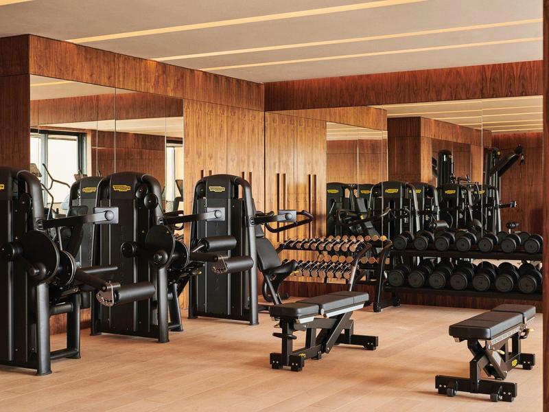 Interior of a gym with wood paneling, exercise machines, and mirrored wall.