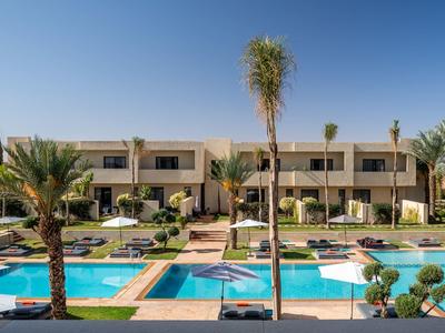 Complesso alberghiero moderno con due piscine e palme sotto un cielo sereno