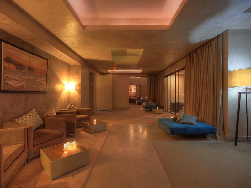 Salon d'hôtel chaleureux et confortable avec canapés, coussins et éclairage tamisé.