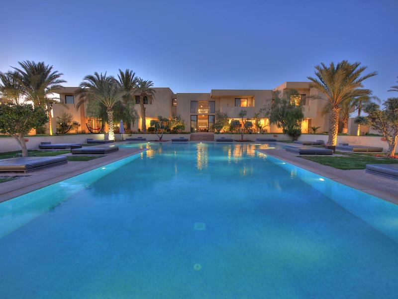 Piscine moderne d'hôtel avec palmiers et ambiance calme en soirée.