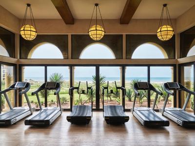 Gimnasio con varias cintas de correr y grandes ventanas con vistas a árboles y edificios