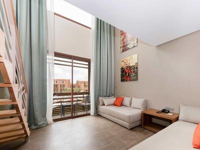 Salon moderne avec canapé, escalier en bois et accès au balcon avec vue sur la ville.