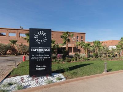 Entrée de l'hôtel avec panneau et bâtiment rouge sous un ciel clair.