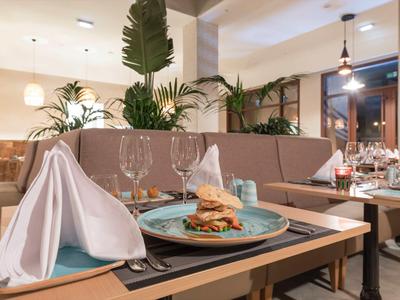 Restaurant moderne avec des tables élégamment dressées et un burger servi sur une assiette bleue.