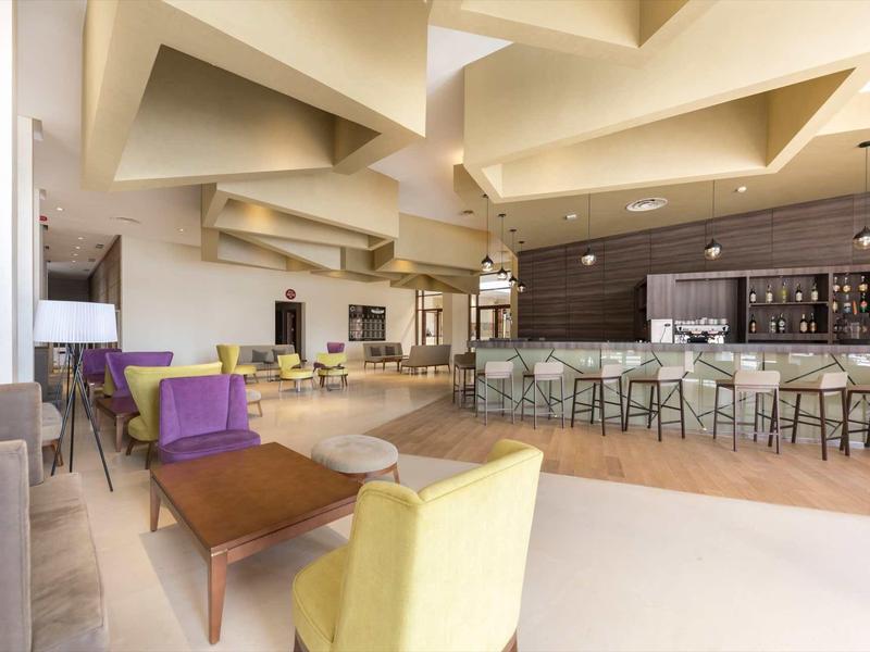 Bar d'hôtel lumineuse avec mobilier moderne et espaces de détente chaleureux.