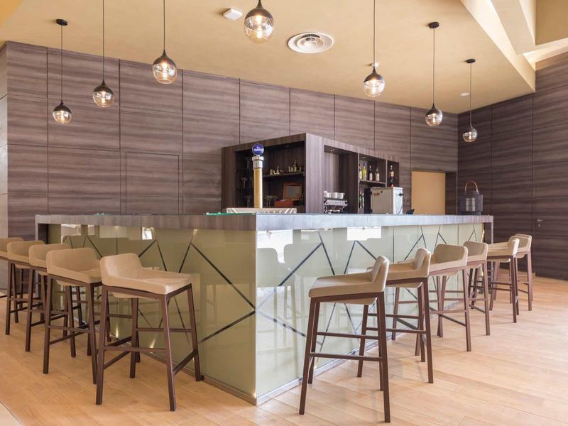 Espace bar d'hôtel moderne avec tabourets en bois et éclairage élégant.