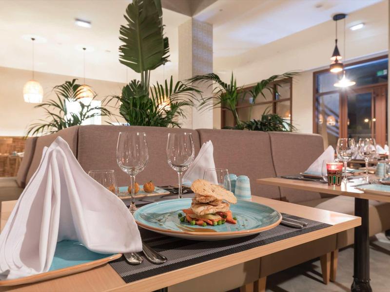 Restaurant moderne avec des tables élégamment dressées et un burger servi sur une assiette bleue.