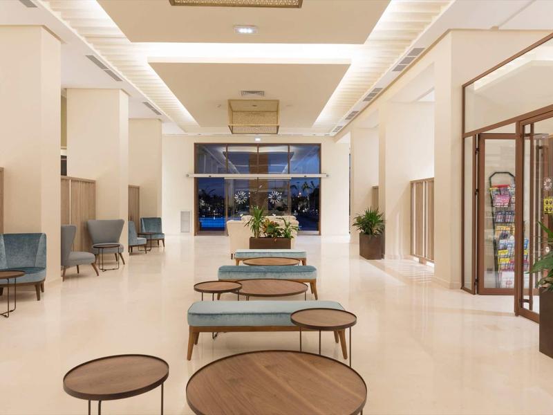 Hall d'hôtel lumineux avec groupes de sièges modernes et grandes fenêtres, design minimaliste.