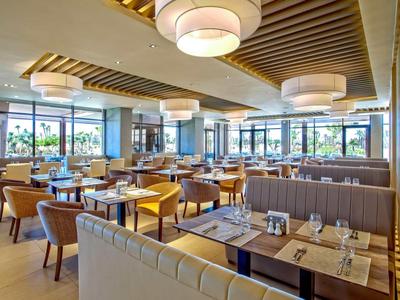 Jasna, nowoczesna restauracja z wygodnymi miejscami do siedzenia i dużymi oknami.