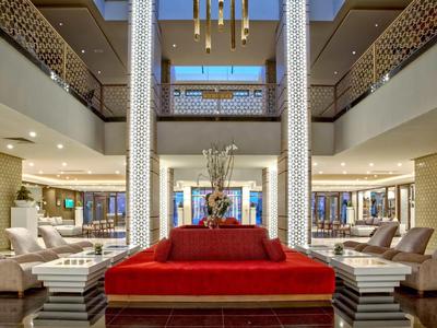 Spacious hotel lobby with red sofa, elegant chairs, and modern lighting.