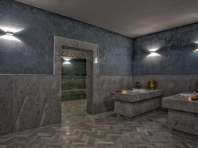 Elegancka strefa wellness z marmurowymi leżakami, stonowanym oświetleniem i dostępem do łaźni parowej.