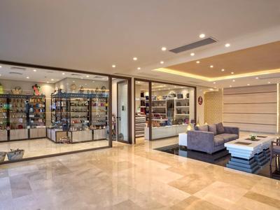 Modern, open hotel lobby area with sofas, armchairs, and access to a retail space.