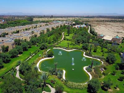 Velká hvězdicovitá vodní plocha obklopená zelení a cestami v hotelovém komplexu.