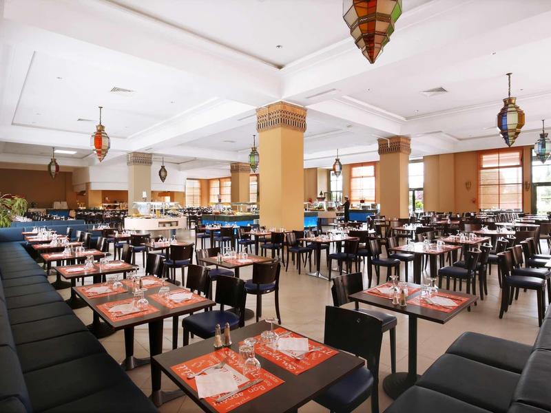 Velká, světlá jídelna s mnoha stoly a židlemi v moderním designu.