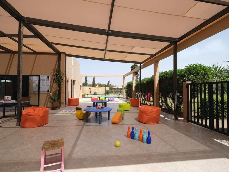 Zastřešená venkovní plocha s barevnými sedacími vaky, stoly a kužely.