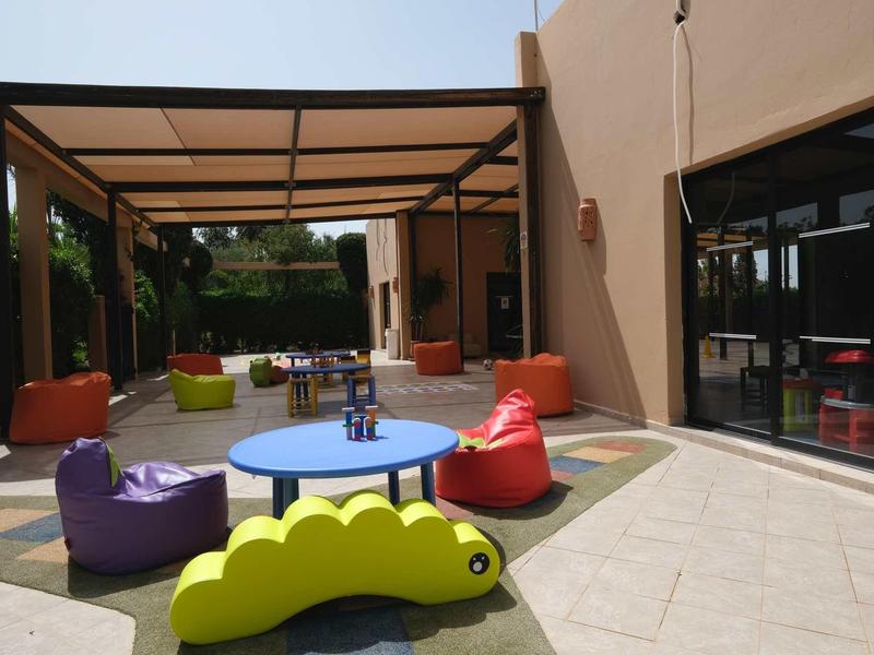 Barevné sedací vaky a stoly pod zastřešeným venkovním prostorem hotelu.