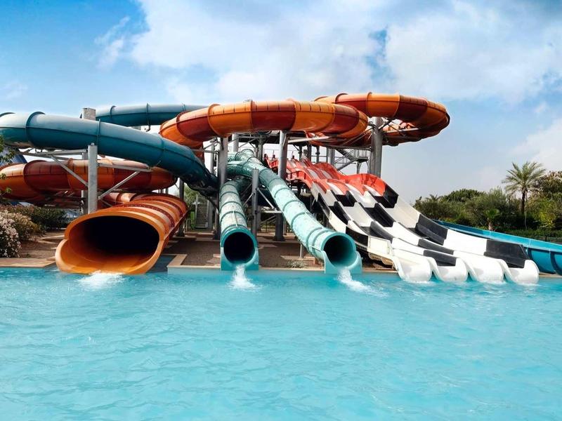 Různobarevné vodní skluzavky vedoucí do velkého modrého bazénu.