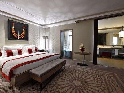 Camera d'hotel moderna con letto grande, area salotto e bagno aperto.