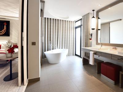 Bagno d'hotel moderno con vasca autoportante e grande specchio sopra i doppi lavandini.