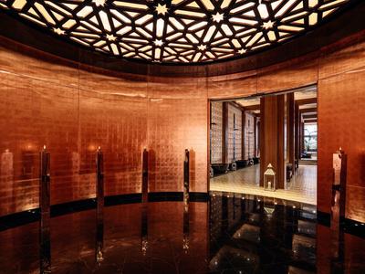 Stanza rotonda moderna con pareti in legno e specchi e illuminazione geometrica sul soffitto.